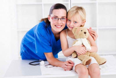 happy nurse and a child holding a teddy bear
